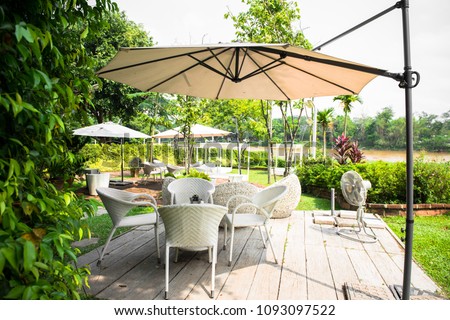 Wicker furniture, outdoor chair set and white umbrella in the garden