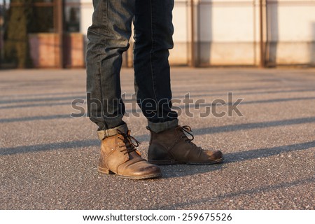 Men\'s legs with jeans and boots. Hipster at sunset.