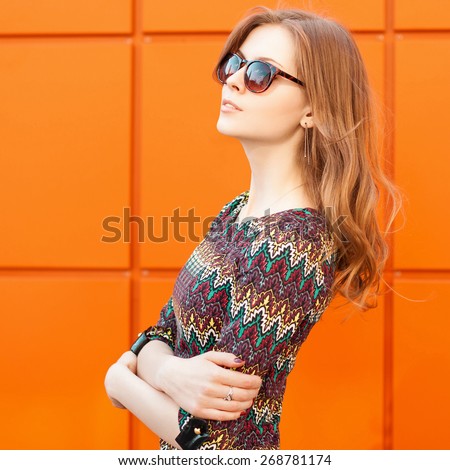 Beautiful and fashion girl  in summer sunny day, close-up portrait. Background of a bright orange wall.