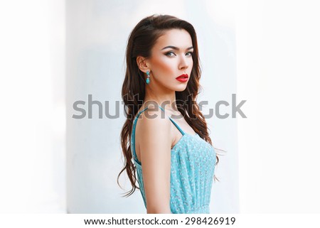 Portrait of beautiful woman with red lips and a turquoise dress on a white background