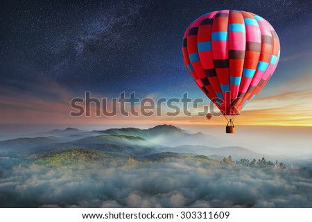 Colorful hot-air balloons flying over the mountain with with stars. Beautiful mountains landscape with clouds at sunset