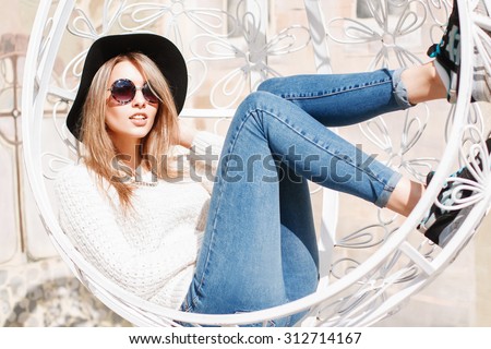 Beautiful young girl resting in a suspended white chair.