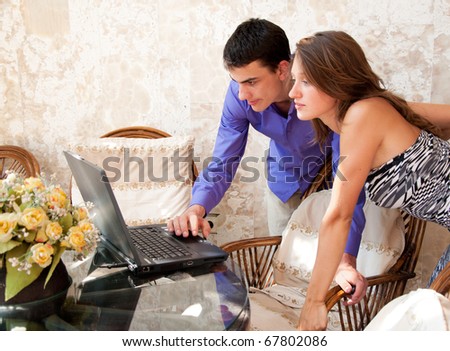 Young man showing something in laptop to young woman