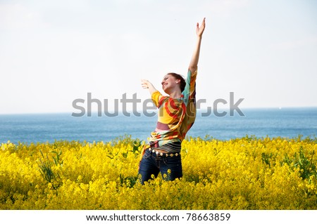 Young happy woman dancing in yellow flowers