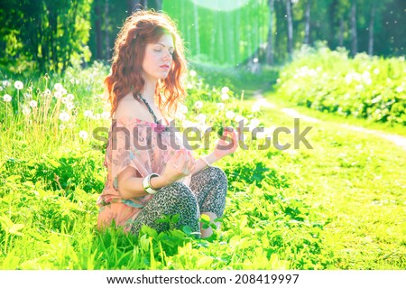 Young woman sitting calm in lotus posture outdoors