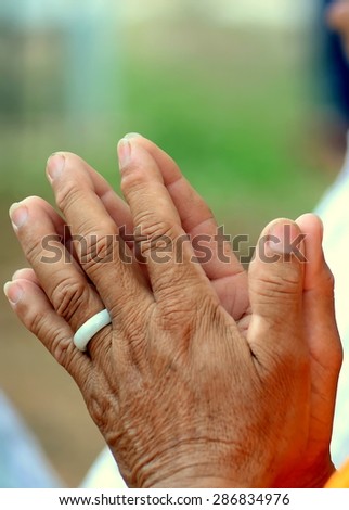 Old man press the hands together at the chest in sign of respect for Buddha