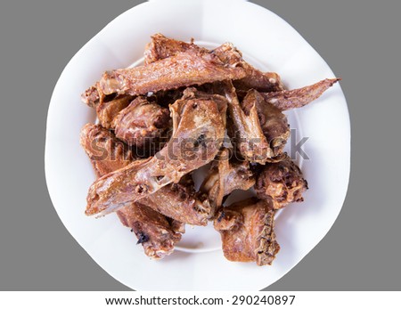 Pieces of  fried duck head , wings, neck and basil,  close up in white plate on gray background.select focus.