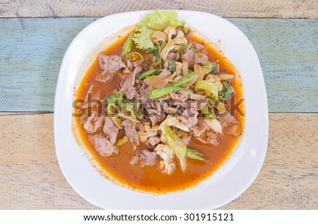 Fried basil pork with chili and cow pea slice in white plate on wood background .Thai food. Traditional food of Thailand. select focus.