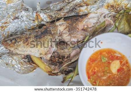 Roasted snake-head fish with salt coated in foil with sauce,sour and spicy on white plate,Thai style food.