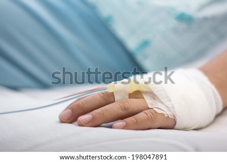 Left hand of the patient on clean bed in the hospital.