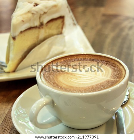 Hot coffee and cake in the white materials on the wood table.
