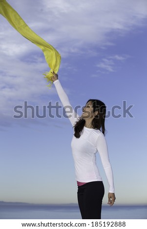 Asian girl having fun with a yellow scarf in the morning at Laguna beach, California