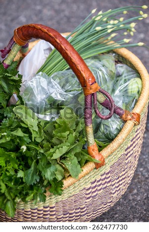 Basket of a shopper contains green vegetable at an organic farmer\'s market
