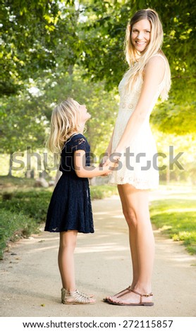 Beautiful Caucasian ethnicity mother and daughter bonding at park with mom looking into camera