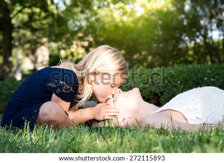 Beautiful Caucasian ethnicity daughter kissing her mother in the forehead at park
