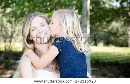 Beautiful Caucasian ethnicity daughter kissing her mother at park