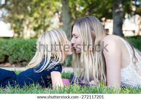 Beautiful Caucasian ethnicity mother and daughter lying on grass and having fun at park