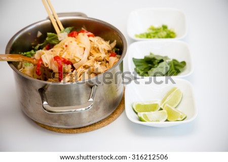 Thai dish of chicken Pad Kee Mao with Bell Pepper and Thai Basil with side garnish of Thai basil, lime, and scallions