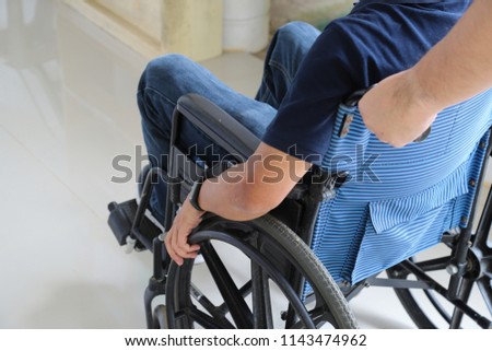 Closeup of a sick man  in wheelchair assists by male assistant in front of the hospital in sunny day.