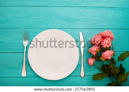 Festive dinner on blue wooden background with bouquet of roses.
