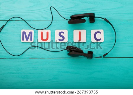 Music word and earphones on wooden background