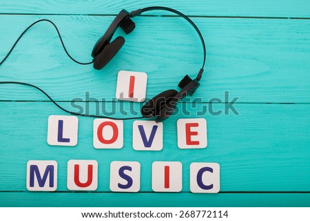 I love music. Letters and headphones on blue wooden background.
