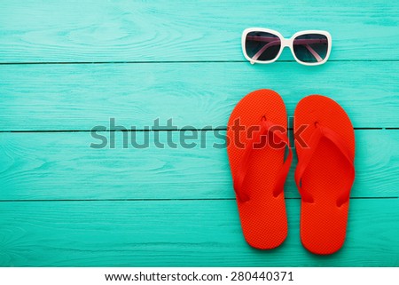 Red flip flops and sunglasses on blue wooden background