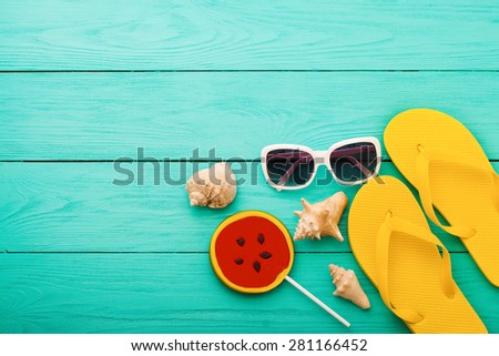 Summer accessories and shells with candy on blue wooden background.