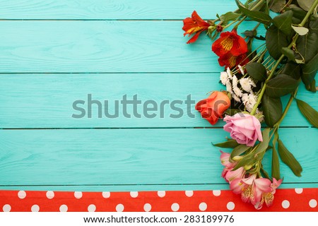 Frame of flowers near tablecloth in polka dots on blue wooden background