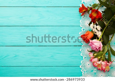 Frame of flowers and lace napkin on blue wooden background. Selective focus