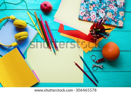 Blue wooden table with education accessories and apple, orange. Top view