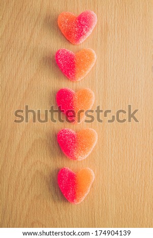 Heart jelly sweets or gummies on wood background. Overhead shot
