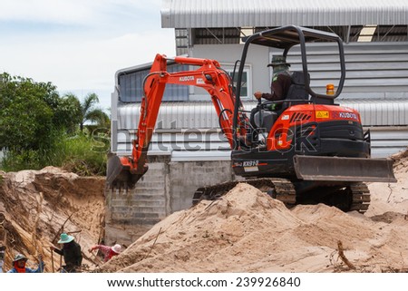 Rayong Thailand - Sep 9 2014: Worker driving excavator to placing sand for construction and several workers were digging sand.