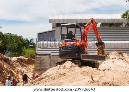 Rayong Thailand - Sep 9 2014: Worker driving excavator to placing sand for construction and several workers were digging sand.