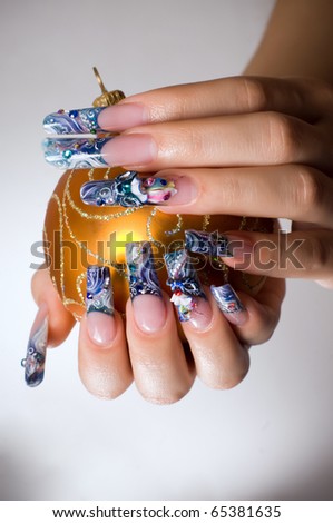 Fingers with beautiful nails holding Christmas toy.