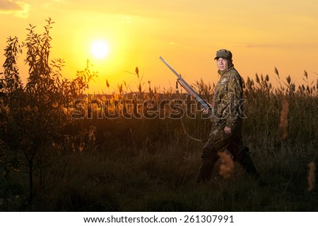 Rifle Hunter Silhouetted in Beautiful Sunset. Summer.