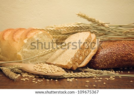 Wheat bread and wheat grain and ears on wooden kitchen table.