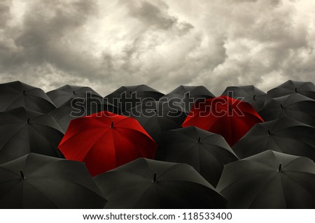 Standing out from the crowd concept, red umbrella among the blacks.
