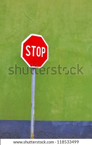 Stop sign on the street against green wall