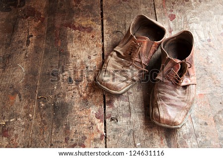 Old shoes on wooden floor. Pair of old dirty brown leather shoes.