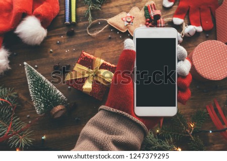 Smartphone in hand for Christmas season mock up with festive holiday decoration in background.