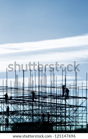 Construction site, silhouettes of workers on scaffolding against the light