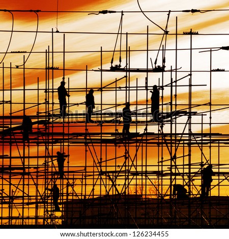 Construction site, silhouettes of workers on scaffolding against the light