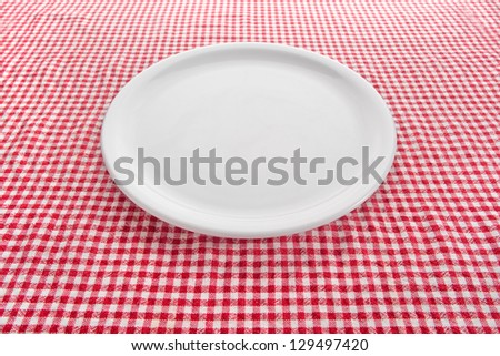 Empty plate. Empty white plate on kitchen table covered with checkered tablecloth.