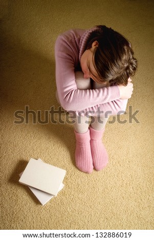 Female student sitting on floor in the dark room, anxiously waiting for the exam day, top view