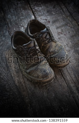 Dirty old leather shoes on wooden floor.