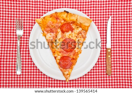 Pepperoni pizza slice on white plate served on table.
