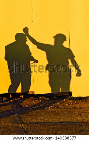 Shadows of two male figures construction workers on construction site.