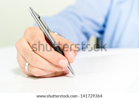 Businessman signing contract. Business man in blue shirt is signing agreement document.