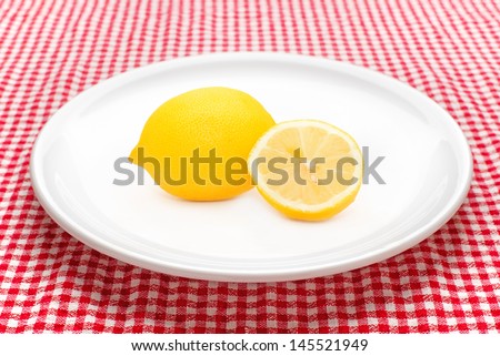 Lemon on white ceramic plate served on kitchen table.